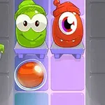 Două personaje animate colorate, unul verde și unul roșu, cu ochi mari și expresii vesele, stau pe rafturi deasupra unei bile portocalii