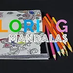 Creioane colorate așezate pe un carnet de colorat cu mandale pe un fundal negru