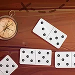 Piese de domino albe pe o suprafață maronie cu un compas în stânga