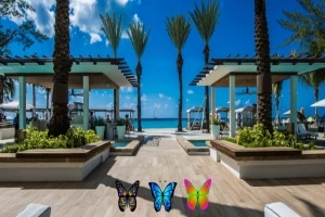 Plajă tropicală cu palmieri, foișoare moderne și fluturi colorați în prim-plan
