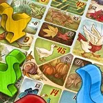 Piese colorate în formă de rațe pe o tablă de joc ilustrată cu imagini de peisaje și animale