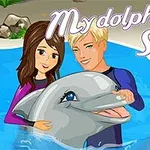 Un bărbat și o femeie zâmbesc în timp ce țin un delfin într-o piscină, cu textul My dolphin Show 2 deasupra