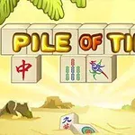 Un aranjament de piese cu litere mari PILE OF TILES pe un fundal de plajă însorită, cu frunze de palmier și pietre