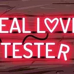 Text neon roz care spune „REAL LOVE TESTER” pe un fundal de lemn