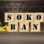 Un buldozer galben într-un depozit mută cutii de lemn inscripționate cu literele „SOKOBAN”