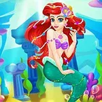 Sirena cu păr roșu și accesorizată cu bijuterii colorate, stă pe fundul oceanului înconjurată de plante marine și ruine antice